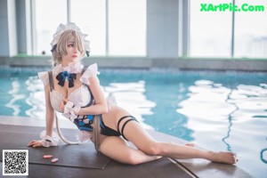 A woman in a maid outfit posing by a pool.