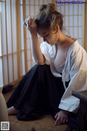 A woman in a white shirt and black skirt drinking from a bottle.