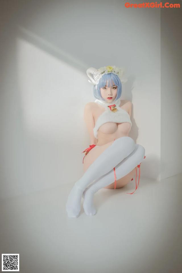 A woman in a white lingerie sitting on a white surface.