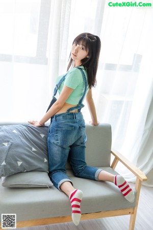 A woman sitting on a couch holding a pillow.