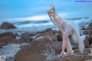 A woman in a white dress standing on a beach.