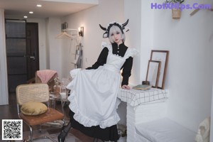 A woman in a black and white dress sitting on a chair.