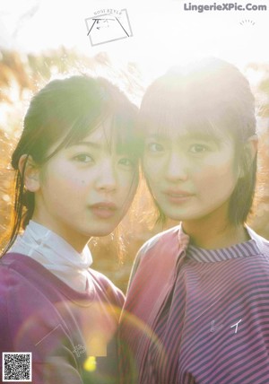 A couple of women standing next to each other near a body of water.