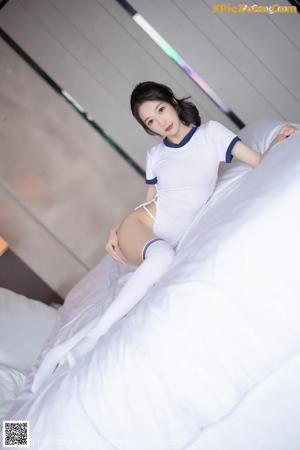 A woman sitting on top of a bed wearing white stockings.