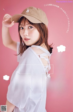 A woman in a white shirt is holding a brown hat.