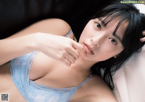 A woman with long black hair laying on a bed.