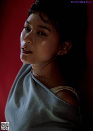 A young woman looking out of a window with a lace curtain.