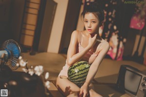 A woman sitting on the floor holding a bowl of food.