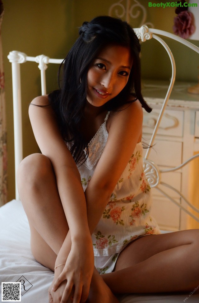 A woman sitting on top of a white bed.