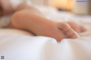A woman in a blue top and panties sitting on a bed.