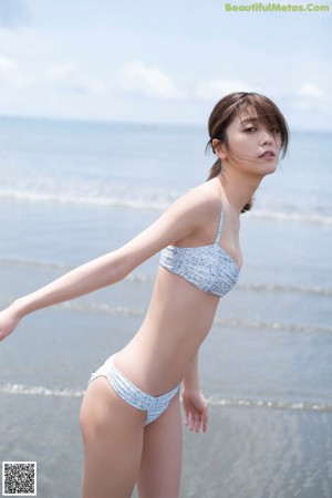 A woman in a blue and white dress standing on a beach.