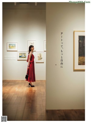 A woman in a red dress standing in front of a poster.