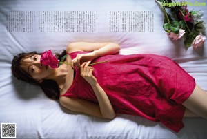 A woman in a red dress sitting on a bed.